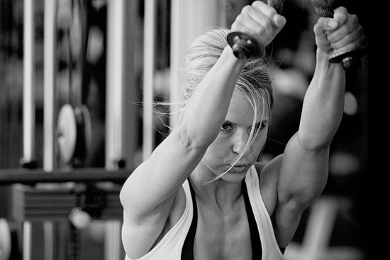 Een vrouw van middelbare leeftijd in de sportschool die de cable row oefening uitvoert.