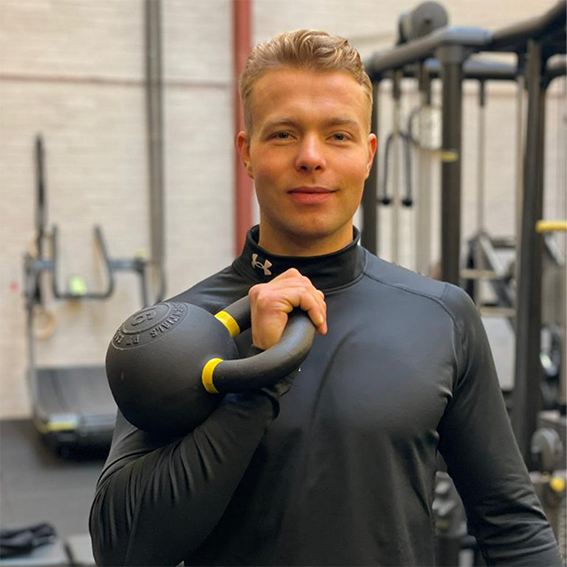 Mannelijke personal trainer in een sportschool met een kettlebell in zijn hand