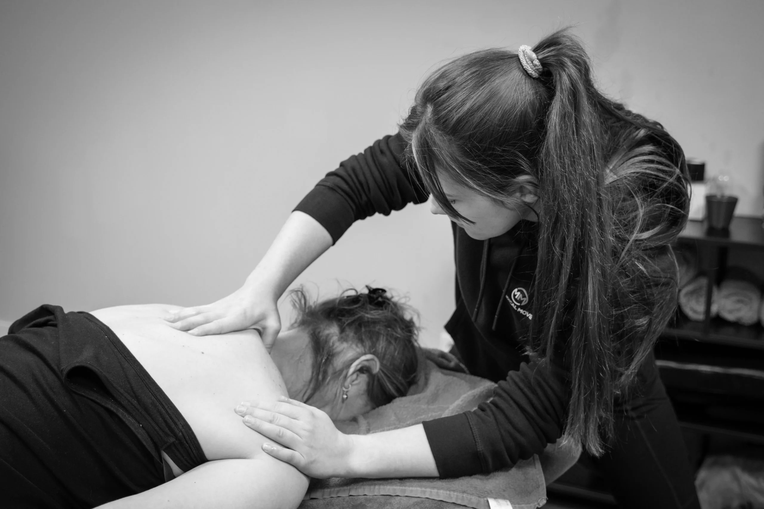 Vrouw in de sportschool die bij een oefening geholpen wordt door een medewerker van de sportschool bij het uitoefenen van een oefening.